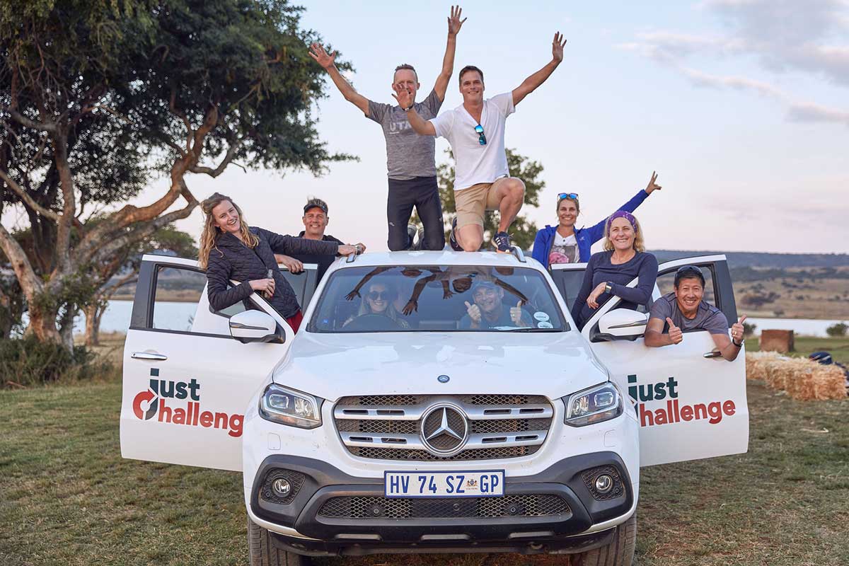 The last challenge team poses for a photo in front of their Mercedes-Benz, showcasing their pride and accomplishment.